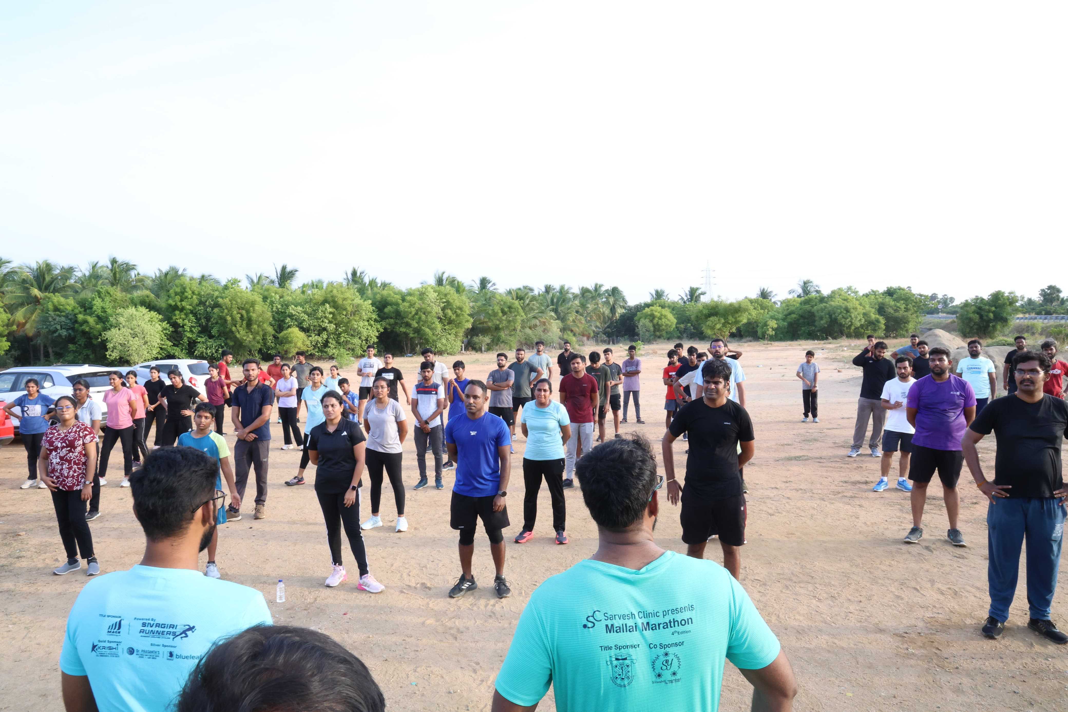 Runners gathered in a wide circle for the morning briefing before the Sunday run, two club leads addressing the group with their backs to the camera.